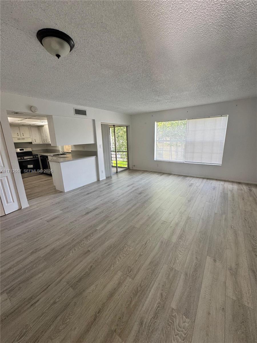 An open-concept living area features light wood-look flooring, a kitchen pass-through, and a sliding door — 4241 NW 19th St # 170, Lauderhill FL 33313, LAUDERHILL, FL