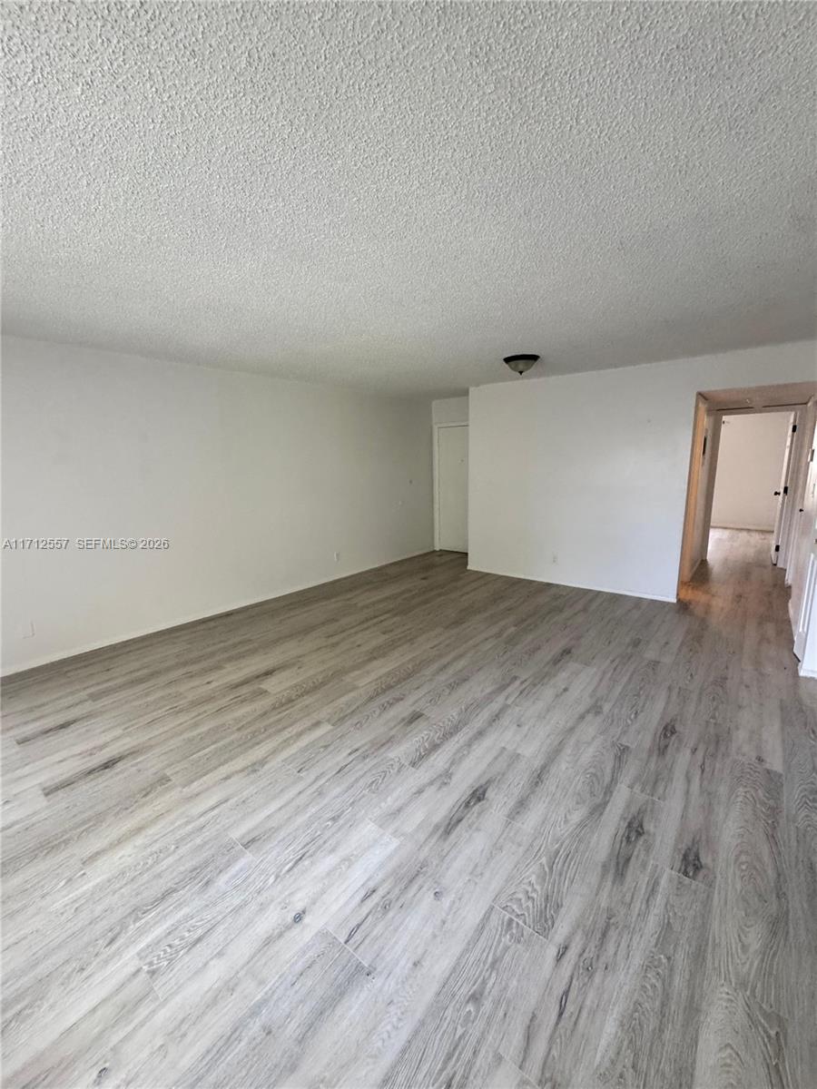 An empty room features light-colored wood-look flooring, white walls, and a textured ceiling — 4241 NW 19th St # 170, Lauderhill FL 33313, LAUDERHILL, FL