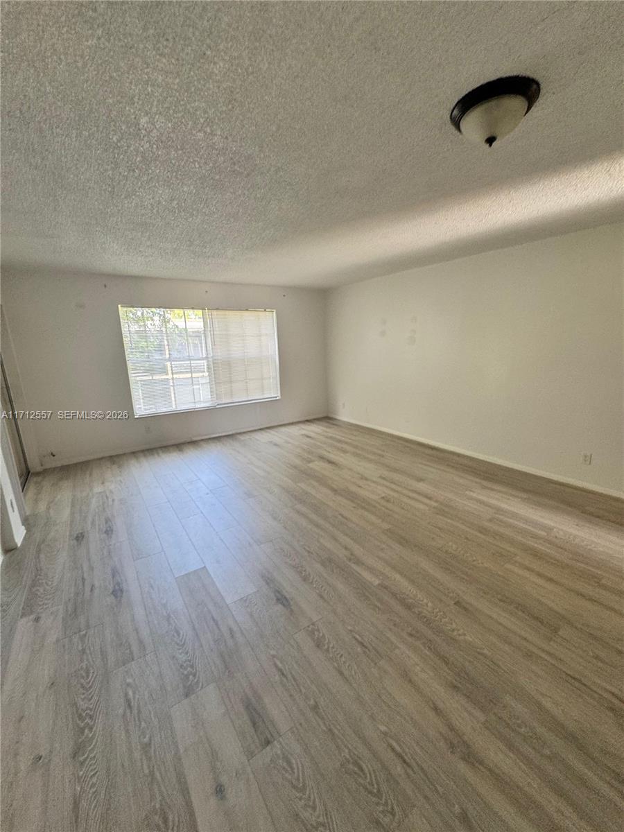 An empty room features light wood-look flooring, white walls, and a single ceiling light fixture — 4241 NW 19th St # 170, Lauderhill FL 33313, LAUDERHILL, FL