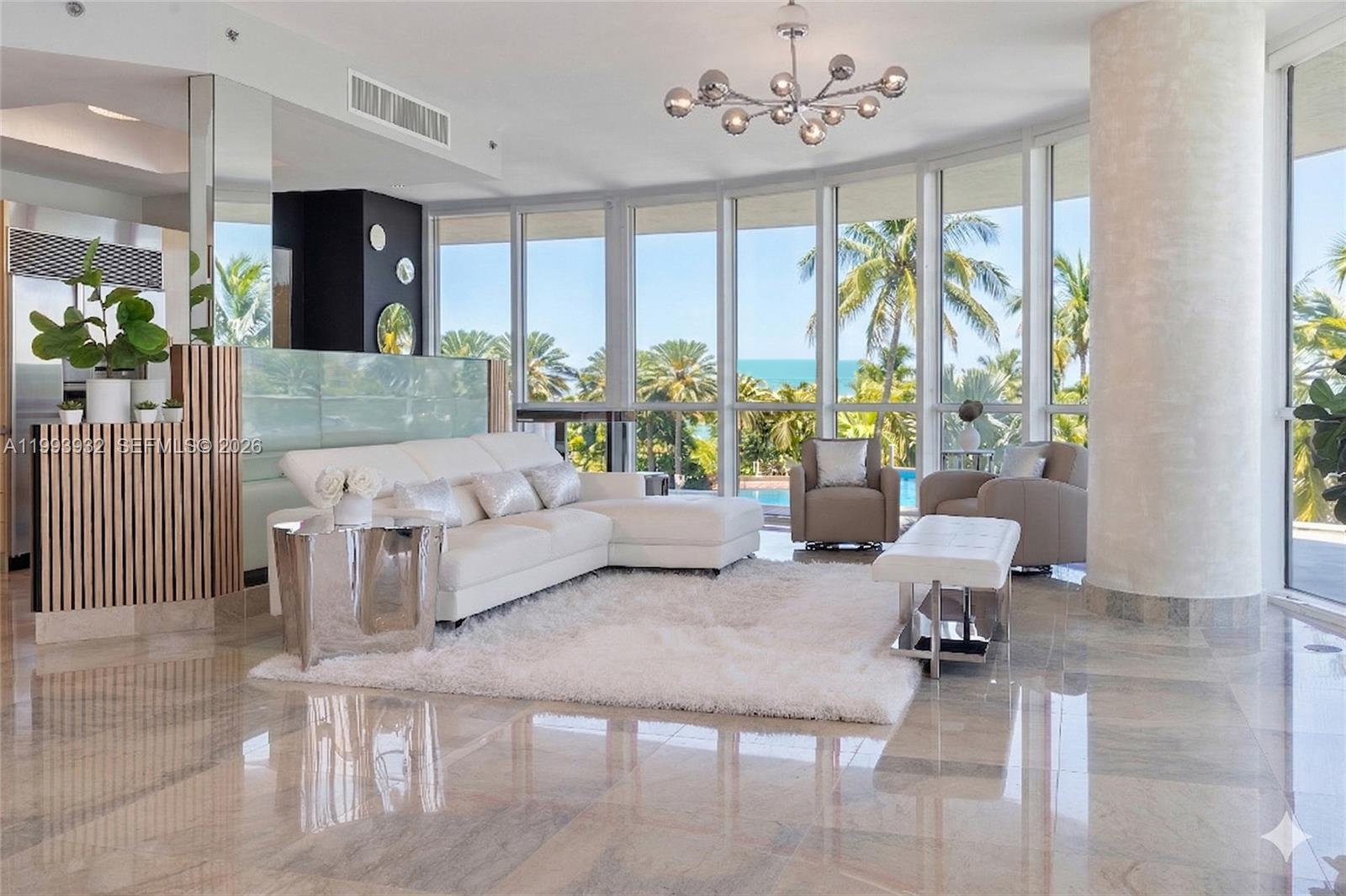 A bright living room features a white sectional, marble floors, and floor-to-ceiling windows overlooking palm trees — 100 S Pointe Dr # 506, Miami Beach FL 33139, MIAMI BEACH, FL