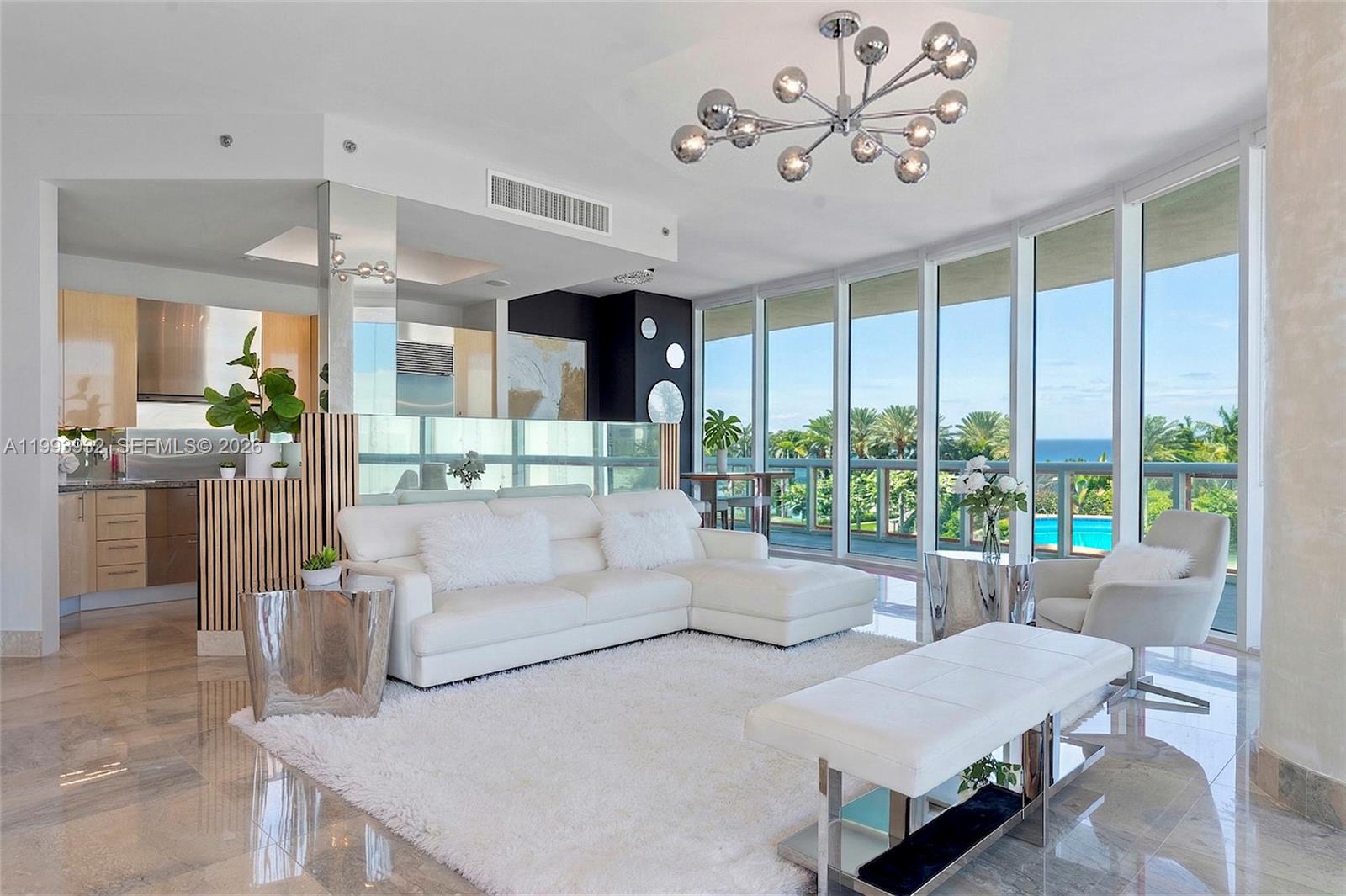 A bright living room features a white sectional sofa, modern chandelier, and floor-to-ceiling windows — 100 S Pointe Dr # 506, Miami Beach FL 33139, MIAMI BEACH, FL