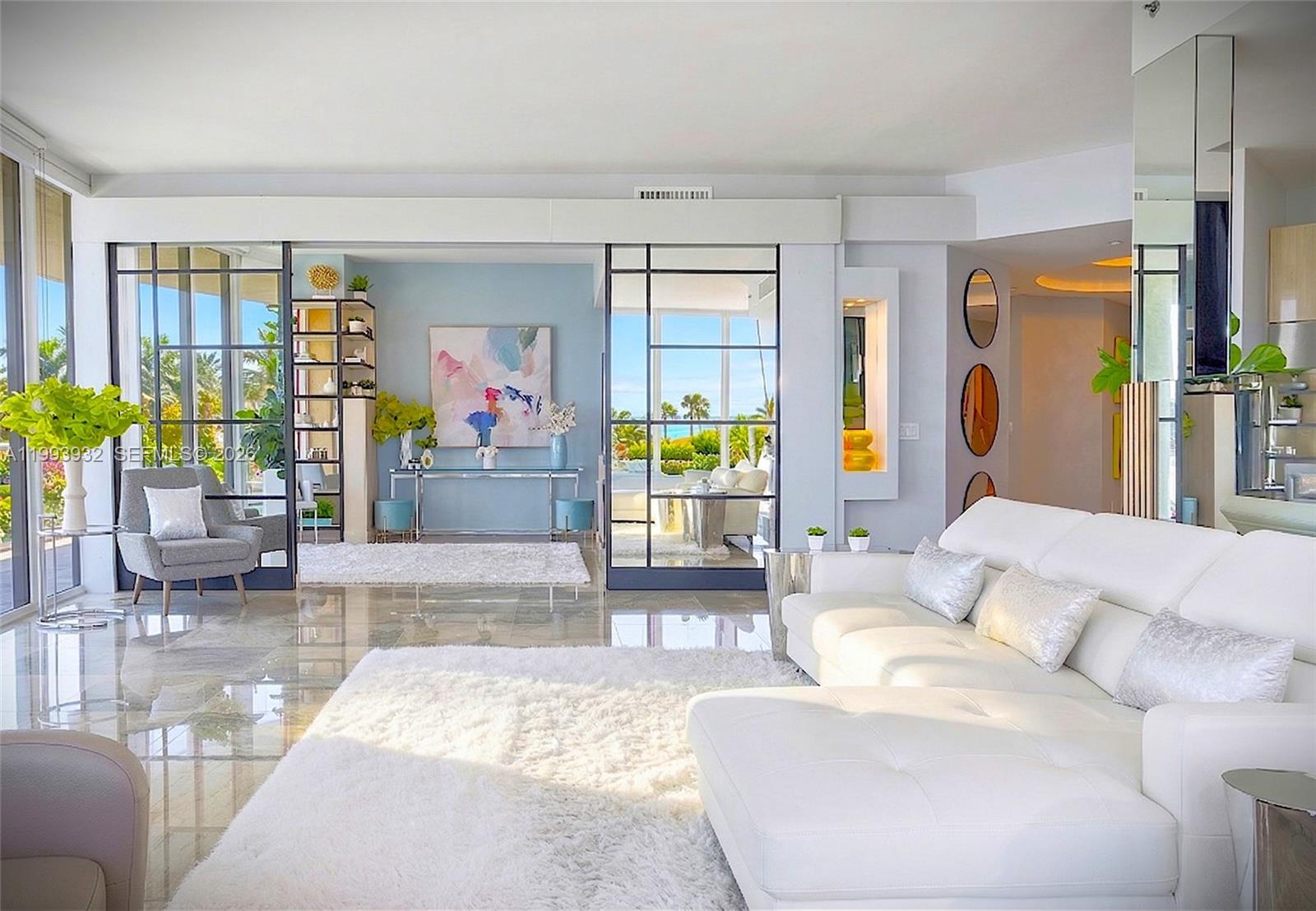 A bright living room features a white sectional, marble floors, and glass-paneled room dividers — 100 S Pointe Dr # 506, Miami Beach FL 33139, MIAMI BEACH, FL