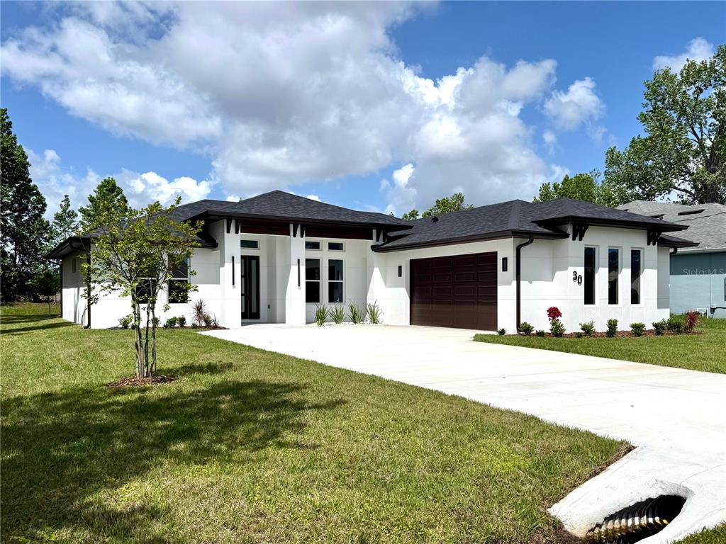 A modern white single-story house with a dark roof and a two-car garage — 30 WOOD CEDAR DR, PALM COAST, FL