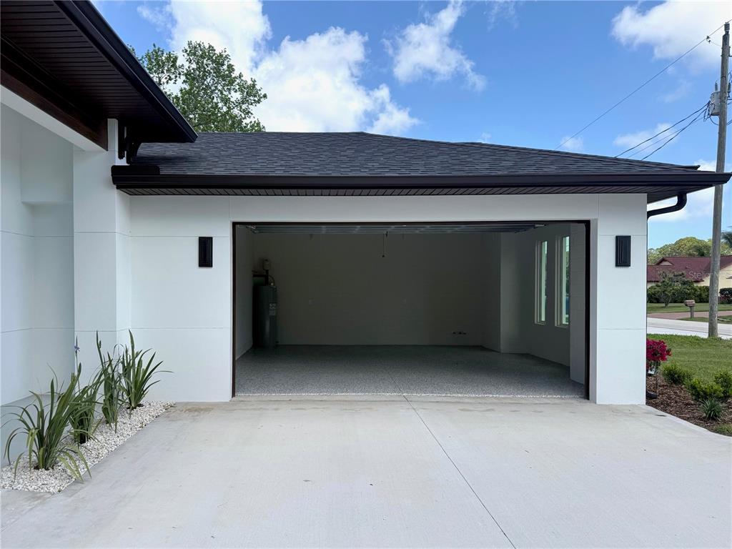 An exterior view of a white garage with a concrete driveway and a dark roof — 30 WOOD CEDAR DR, PALM COAST, FL