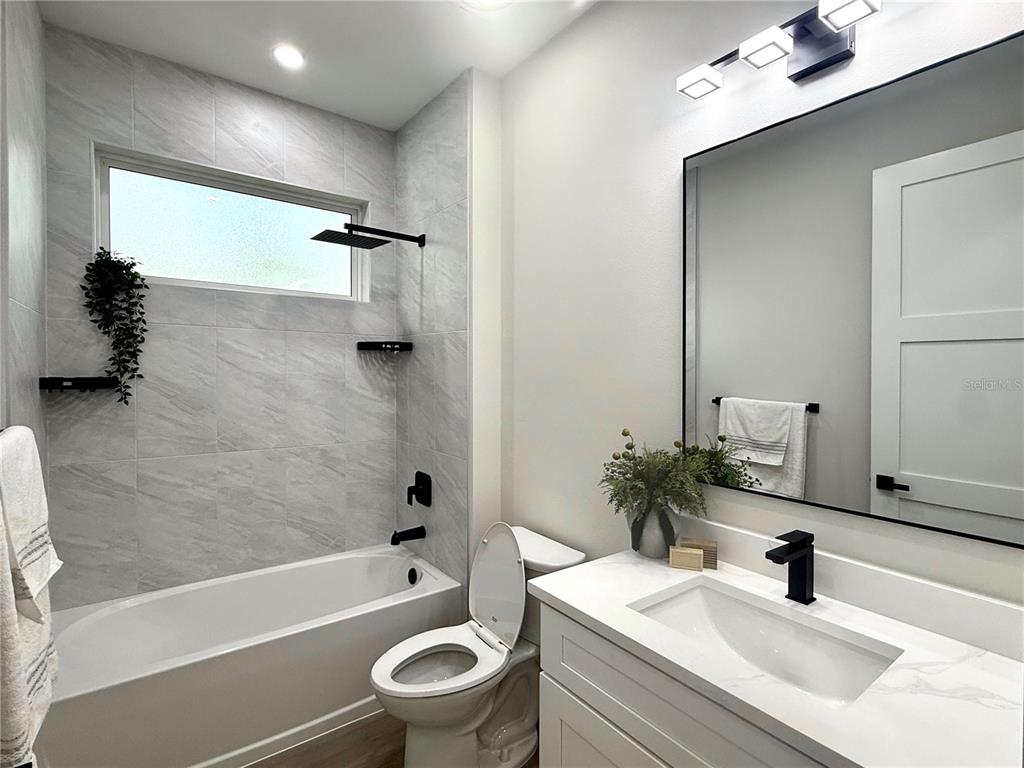 A modern bathroom features a tiled tub-shower combination, a white vanity, and black fixtures — 30 WOOD CEDAR DR, PALM COAST, FL