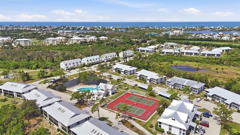 An aerial view shows a residential complex with multiple buildings, a swimming pool, and tennis courts — 6800 PLACIDA ROAD UNIT TH17, ENGLEWOOD, FL