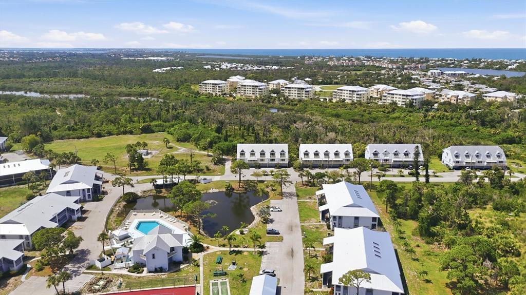 An aerial view shows a residential complex with white buildings, a swimming pool, and greenery — 6800 PLACIDA ROAD UNIT TH17, ENGLEWOOD, FL
