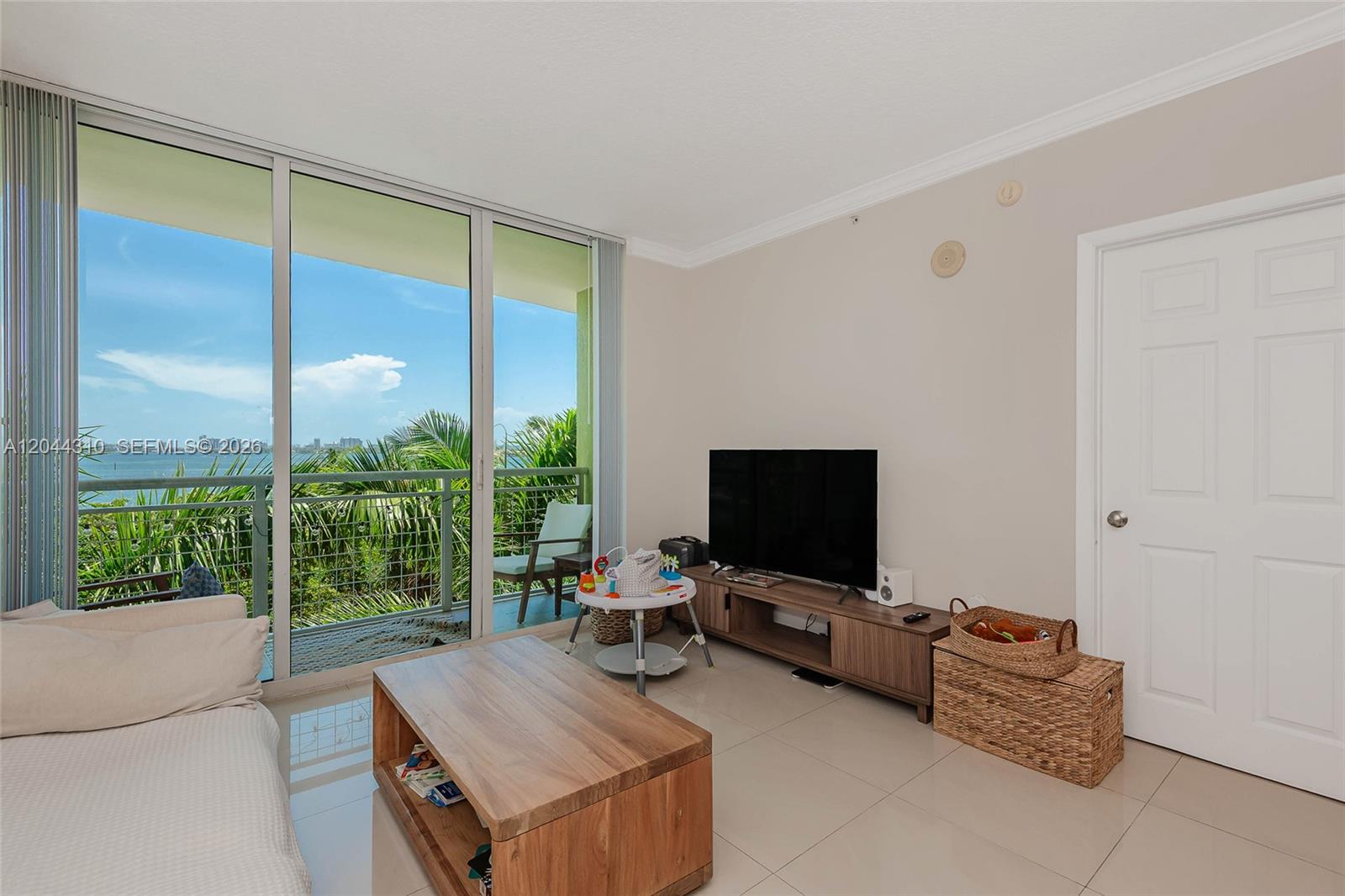 A living room features tile flooring, a television console, and a balcony with water views — 2000 N Bayshore Dr # 516, Miami FL 33137, MIAMI, FL