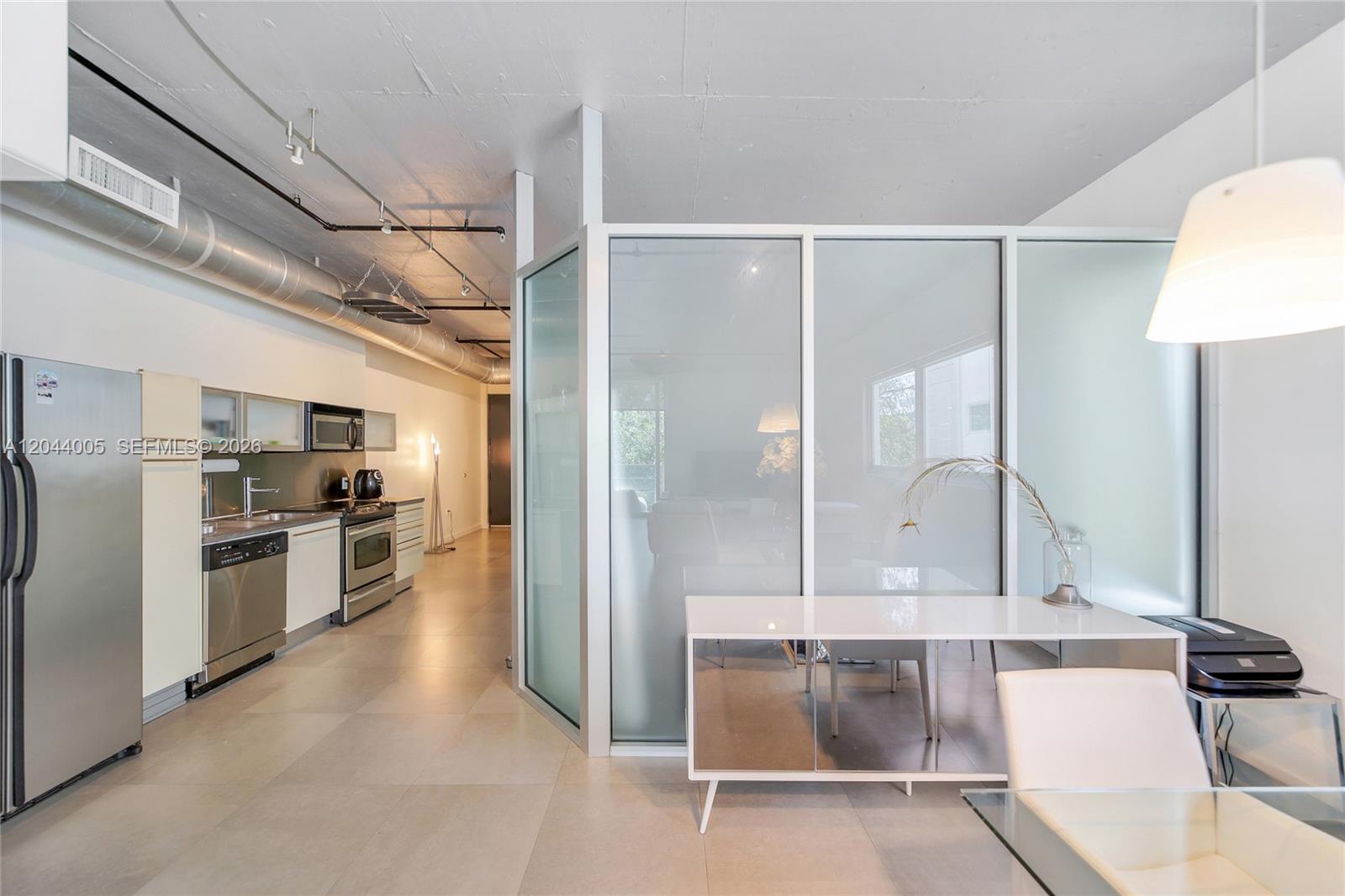 A modern kitchen and dining area feature exposed ductwork, frosted glass partitions, and tile flooring — 1700 Meridian Ave # 310, Miami Beach FL 33139, MIAMI BEACH, FL