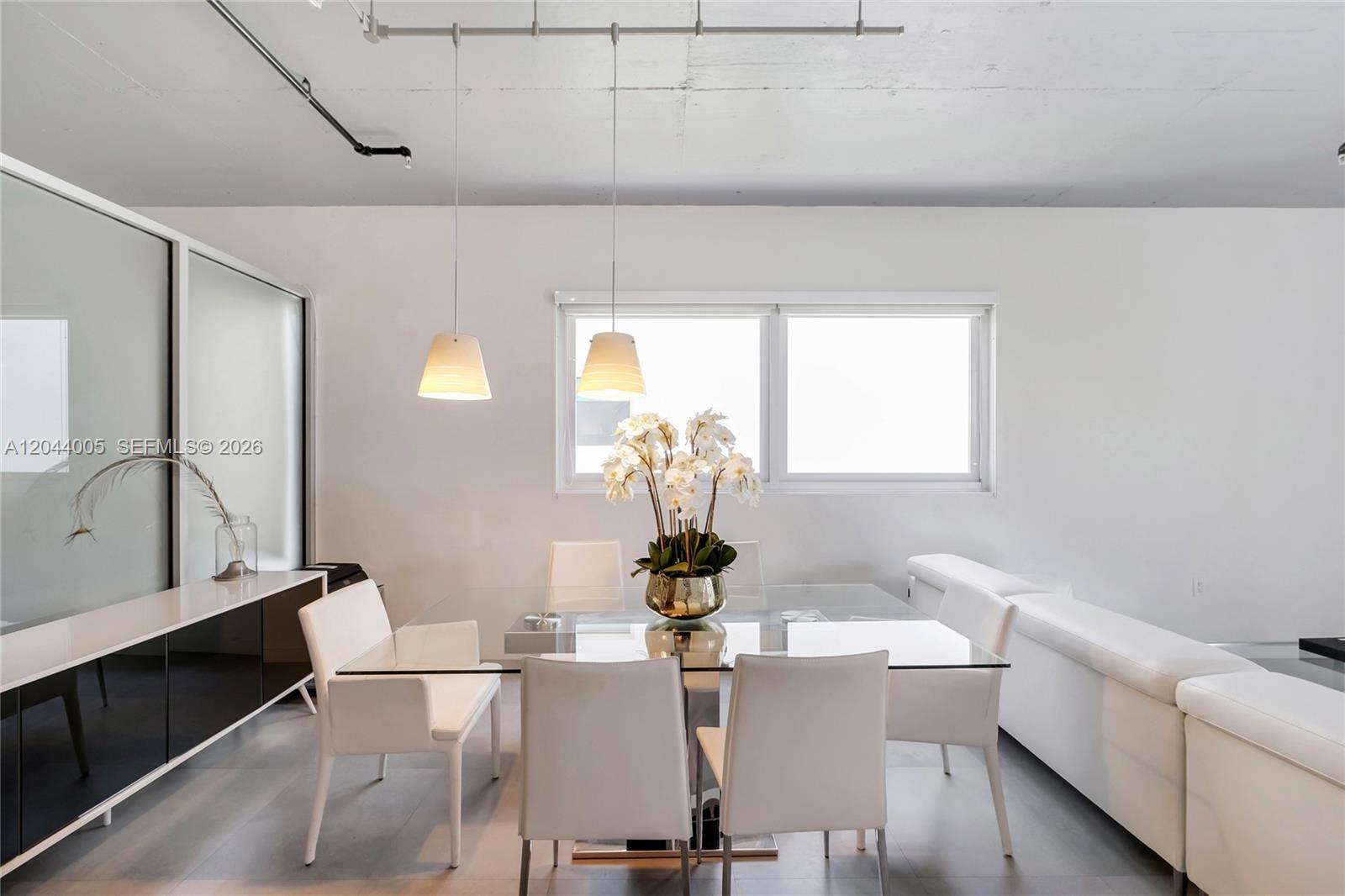 A dining area features a glass table, white chairs, pendant lights, and a white sideboard — 1700 Meridian Ave # 310, Miami Beach FL 33139, MIAMI BEACH, FL