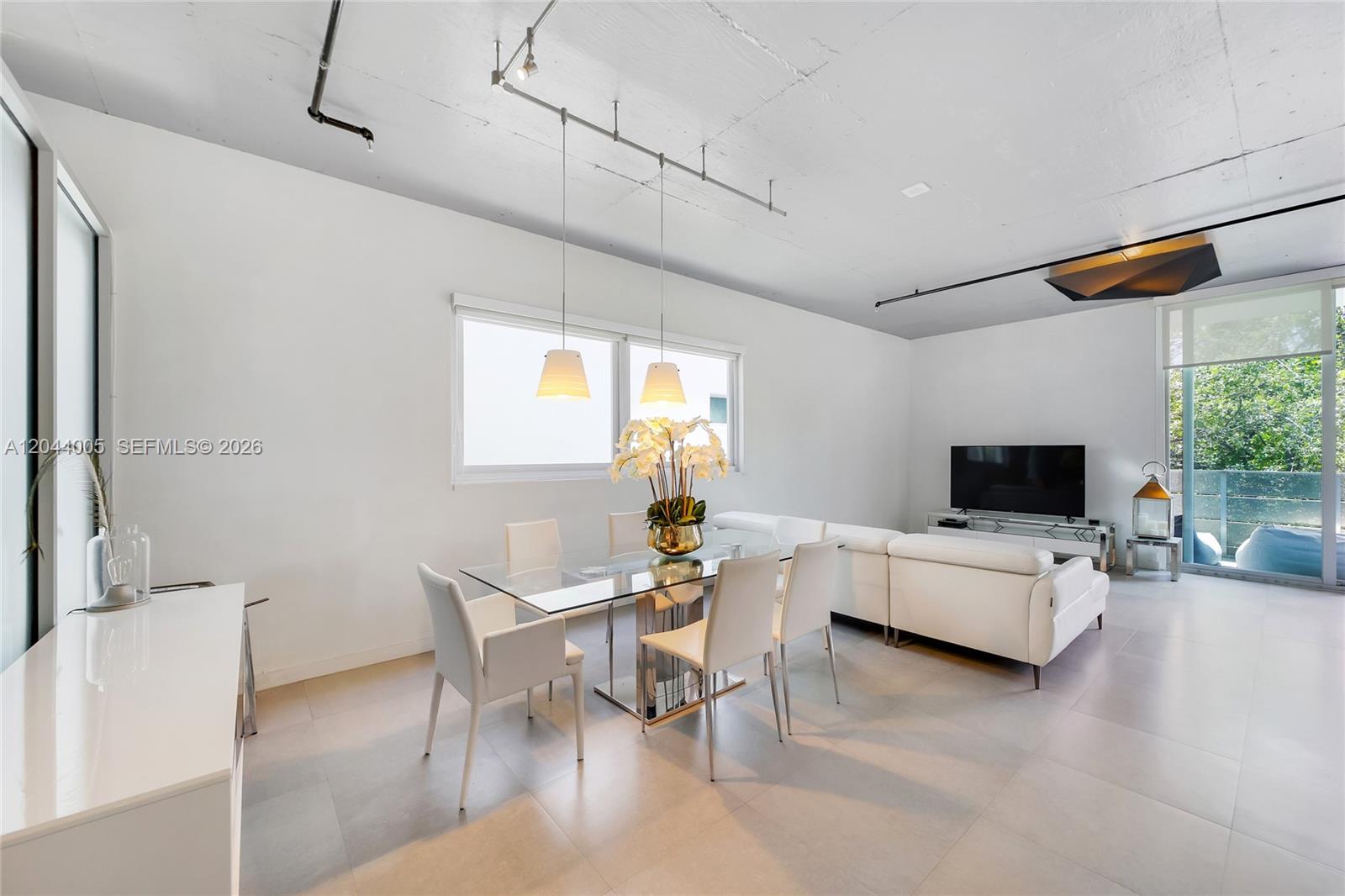 A modern open-concept living and dining area features white furniture, tile floors, and exposed ceilings — 1700 Meridian Ave # 310, Miami Beach FL 33139, MIAMI BEACH, FL