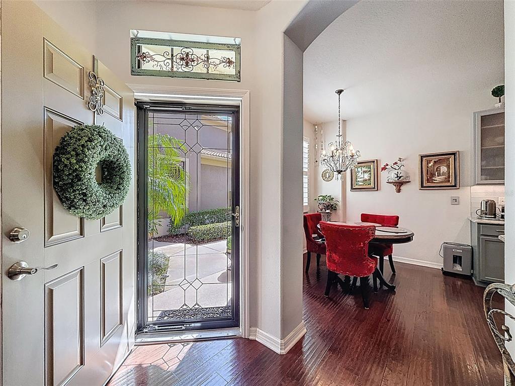 A view from an entryway into a dining room with red chairs and hardwood floors — 2539 SILVERBACK COURT, PALM HARBOR, FL