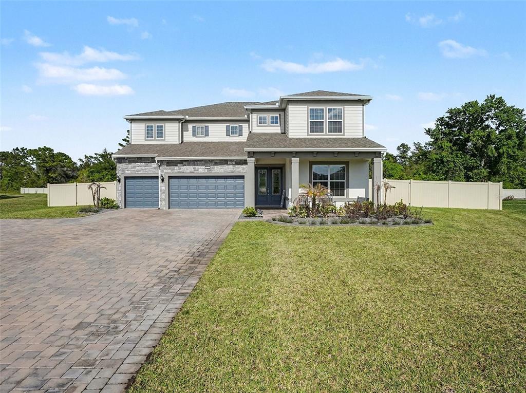 A two-story house with a stone and siding exterior, a three-car garage, and a driveway — 4389 SUNSET PRESERVE BOULEVARD, ORLANDO, FL