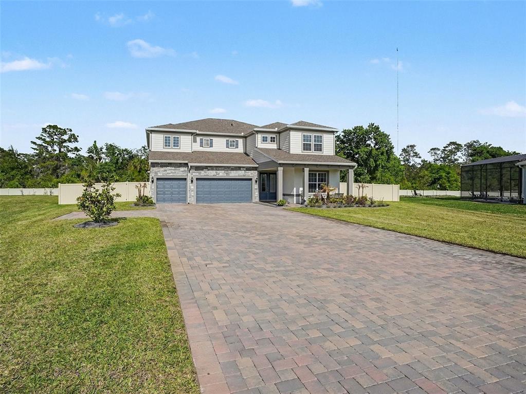 A two-story house with a paved driveway, three-car garage, and a large grassy yard — 4389 SUNSET PRESERVE BOULEVARD, ORLANDO, FL