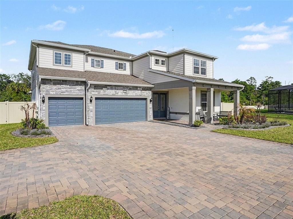 A two-story house with a stone and siding exterior, a three-car garage, and a paved driveway — 4389 SUNSET PRESERVE BOULEVARD, ORLANDO, FL