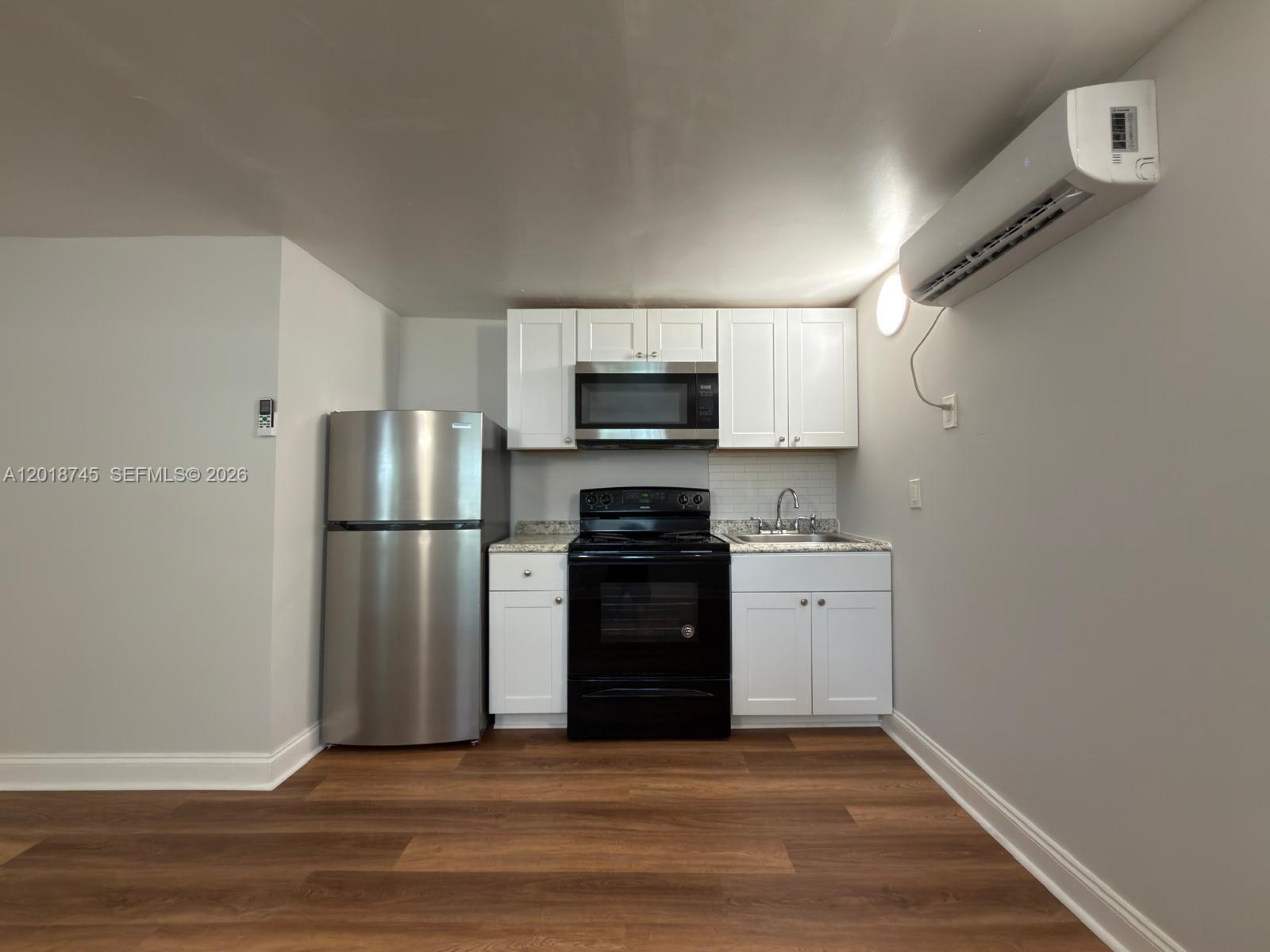 A small kitchen features white cabinets, stainless steel appliances, and wood-look flooring — 10335 NW 2nd Ct # 3, Miami FL 33150, MIAMI, FL