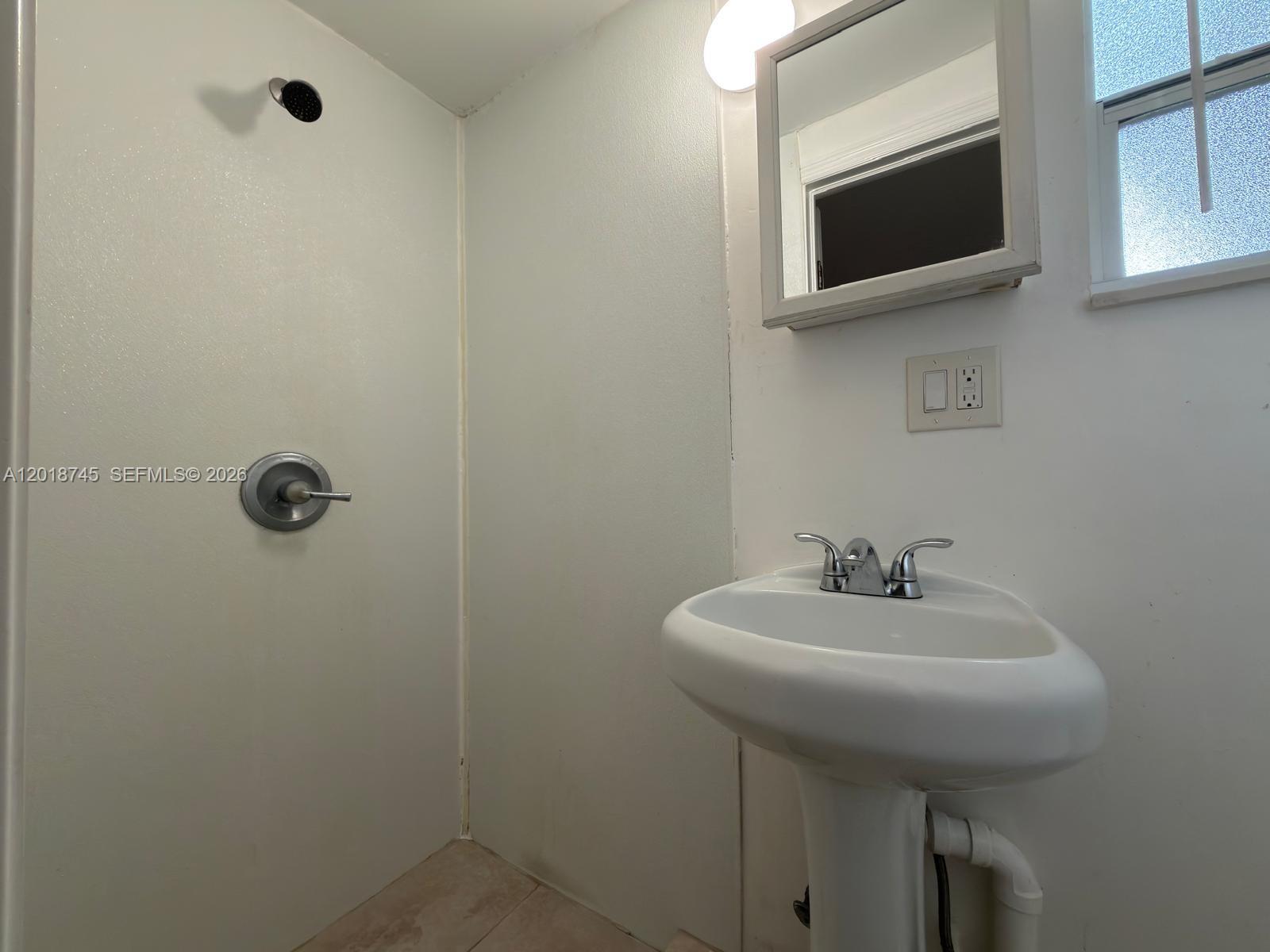 A bathroom features a pedestal sink, a wall-mounted medicine cabinet, and a shower stall — 10335 NW 2nd Ct # 3, Miami FL 33150, MIAMI, FL