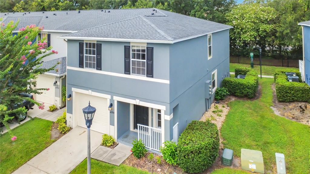 An exterior view of a two-story blue townhouse with a garage and a small yard — 12705 LEXINGTON SUMMIT STREET, ORLANDO, FL
