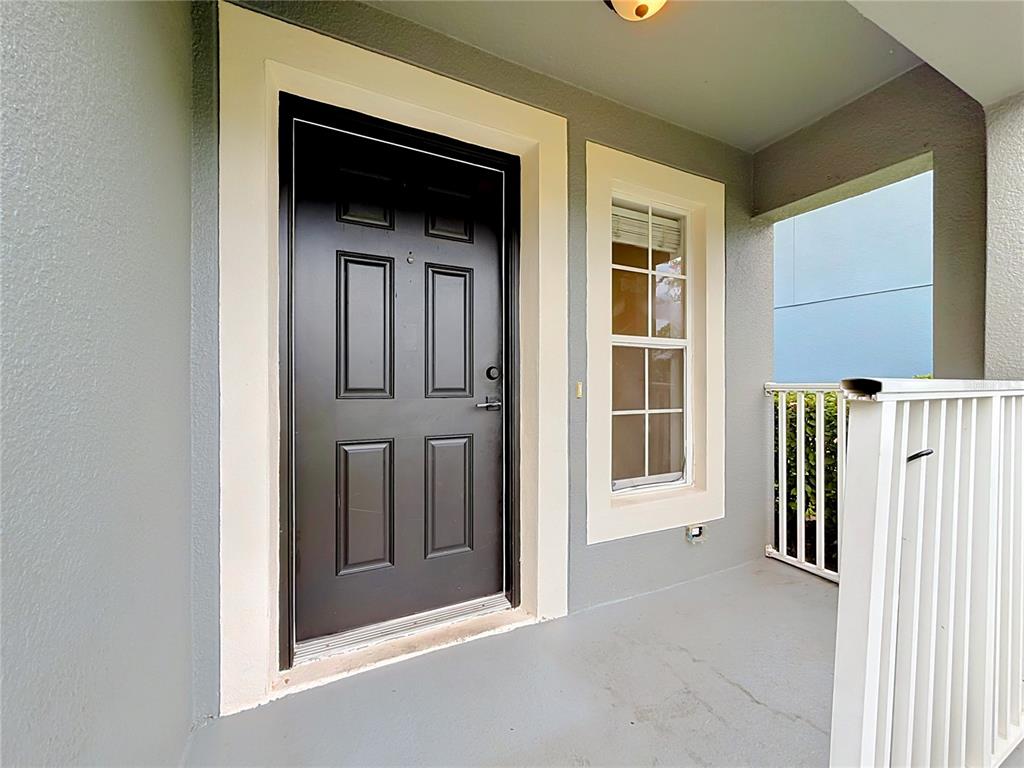 A black front door with a window and white trim sits on a covered porch — 12705 LEXINGTON SUMMIT STREET, ORLANDO, FL