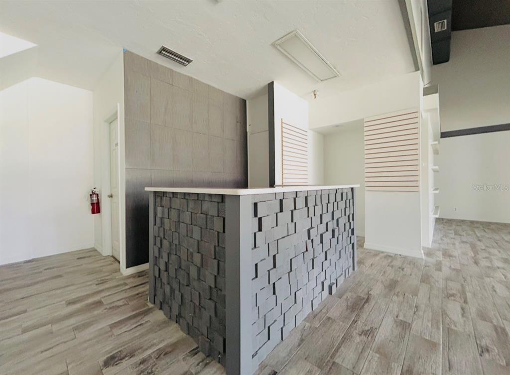 A commercial space features a textured gray reception desk, wood-look tile flooring, and slat walls — 2441 NW 43RD STREET UNIT 25A, GAINESVILLE, FL