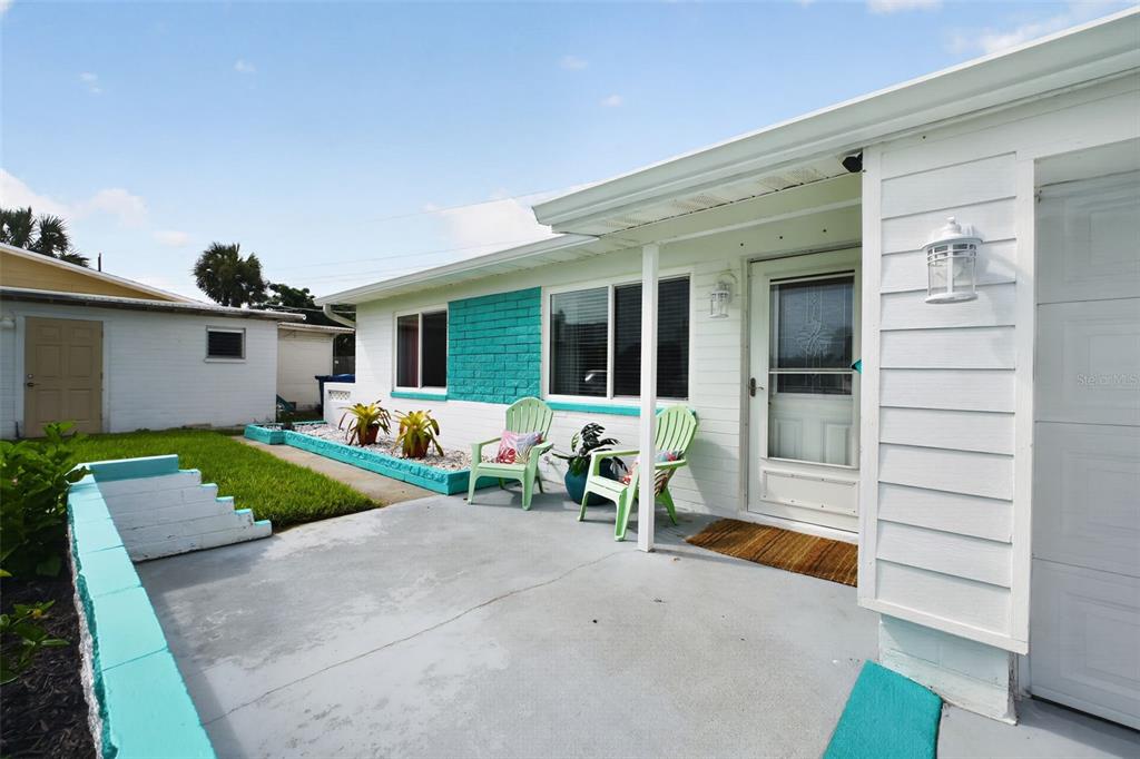 A white house with a turquoise accent wall and a concrete patio with two chairs — 20 SUNNY SHORE DRIVE, ORMOND BEACH, FL