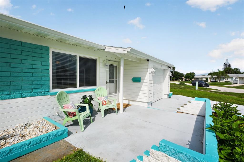 A teal and white house exterior features a concrete patio with two green chairs — 20 SUNNY SHORE DRIVE, ORMOND BEACH, FL