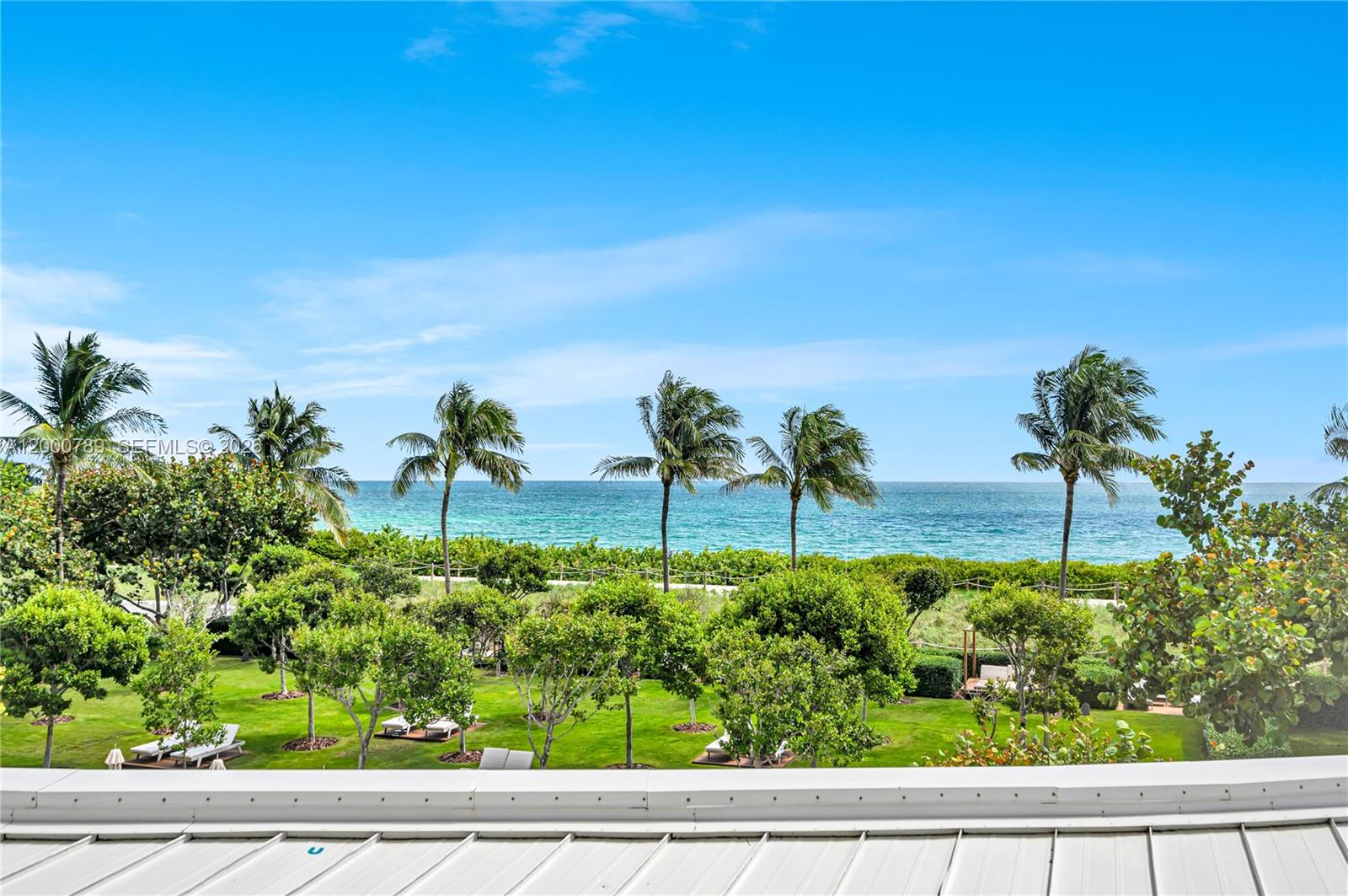 A view of a green lawn with palm trees overlooking the ocean — 9001 Collins Ave # 201, Surfside FL 33154, SURFSIDE, FL