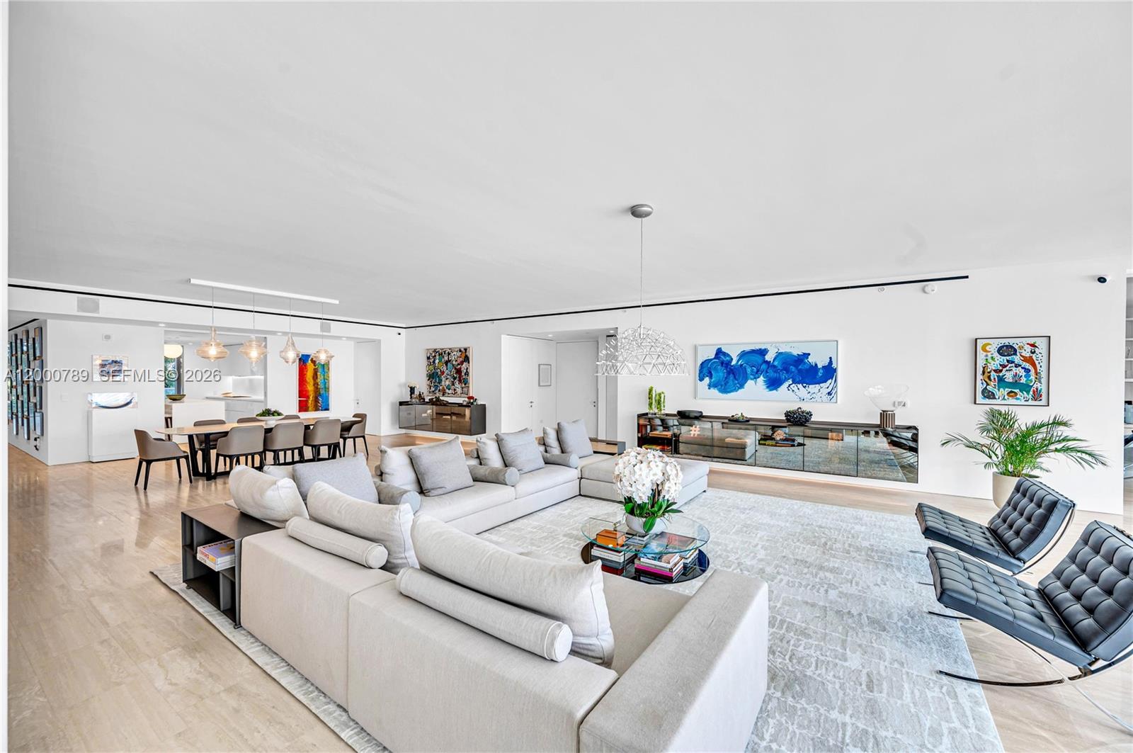 A spacious, modern living and dining area features white walls, light flooring, and contemporary furniture — 9001 Collins Ave # 201, Surfside FL 33154, SURFSIDE, FL