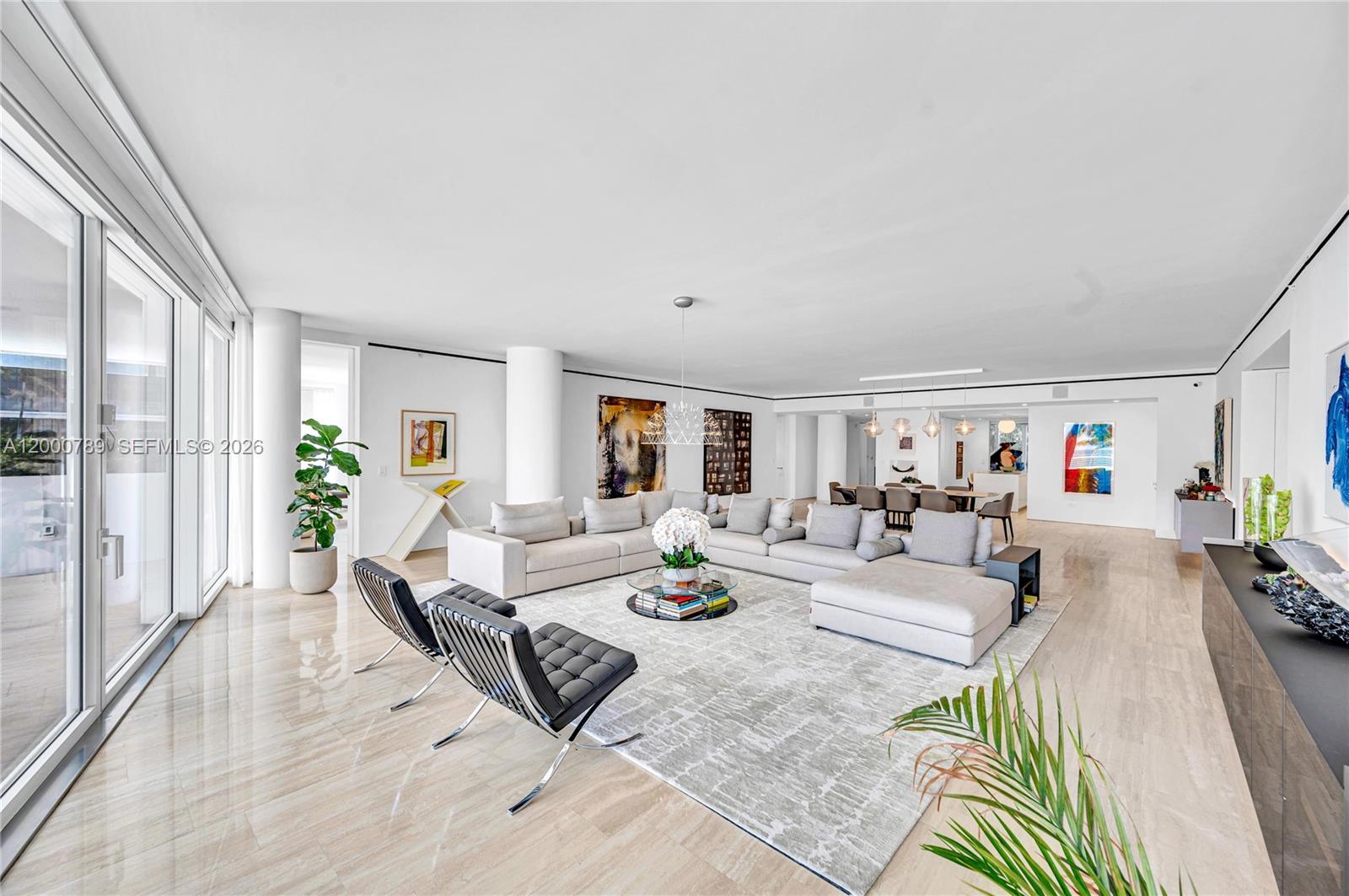 A spacious, open-concept living room features light stone flooring, a large sectional, and modern furniture — 9001 Collins Ave # 201, Surfside FL 33154, SURFSIDE, FL