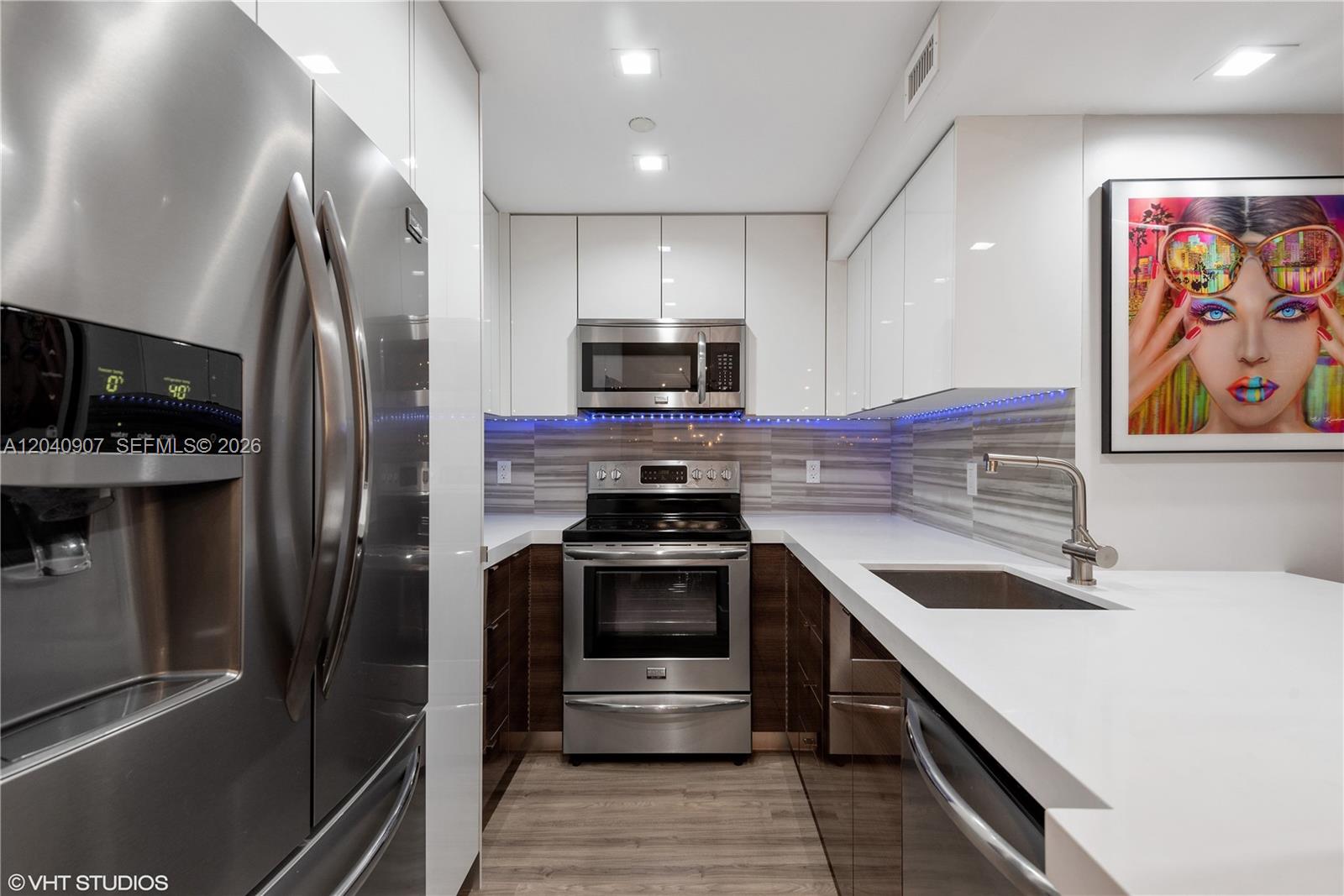 A modern galley kitchen features stainless steel appliances, white upper cabinets, and dark lower cabinets — 1200 West Ave # 1005, Miami Beach FL 33139, MIAMI BEACH, FL