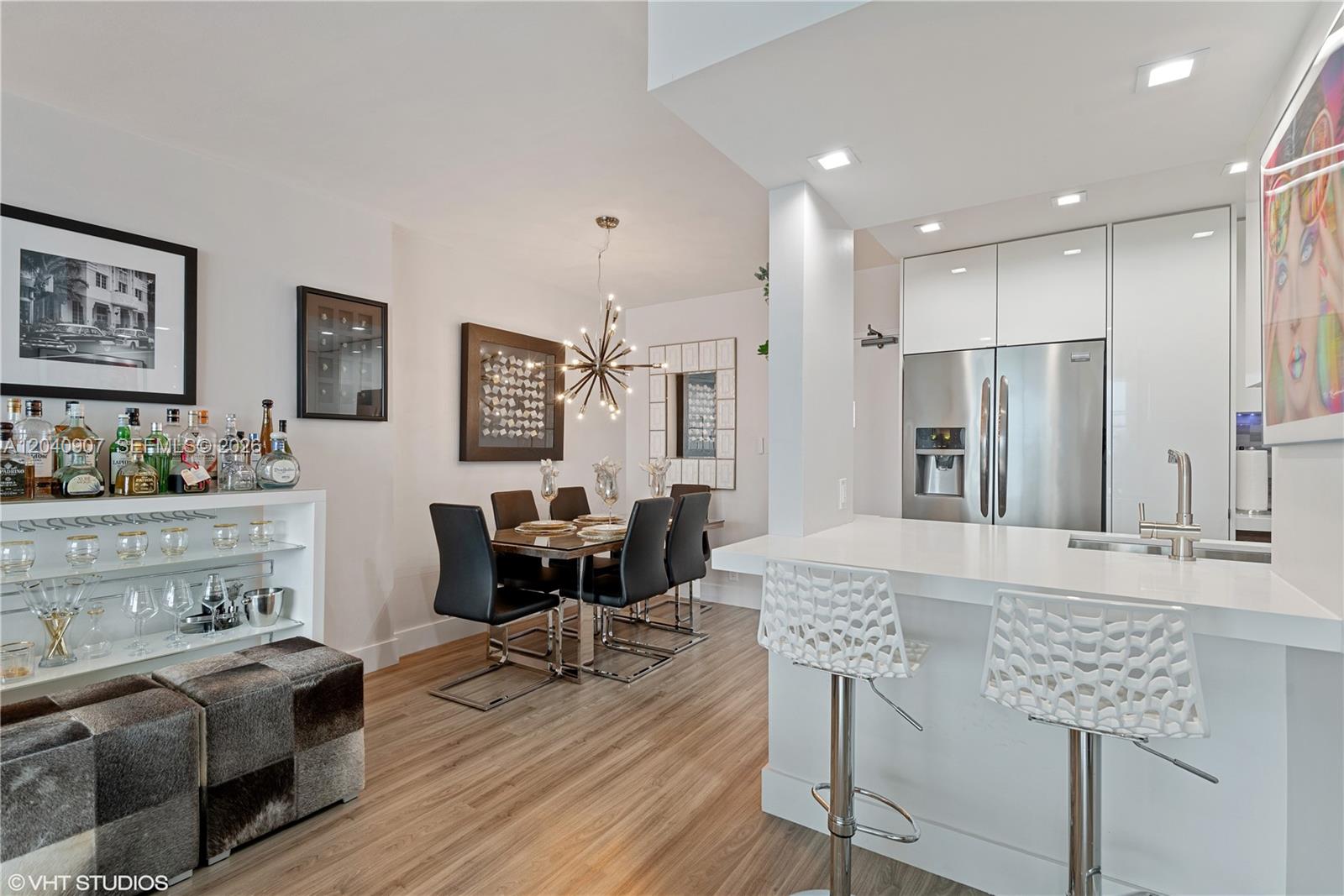 A modern dining area and kitchen feature white cabinetry, stainless steel appliances, and wood flooring — 1200 West Ave # 1005, Miami Beach FL 33139, MIAMI BEACH, FL