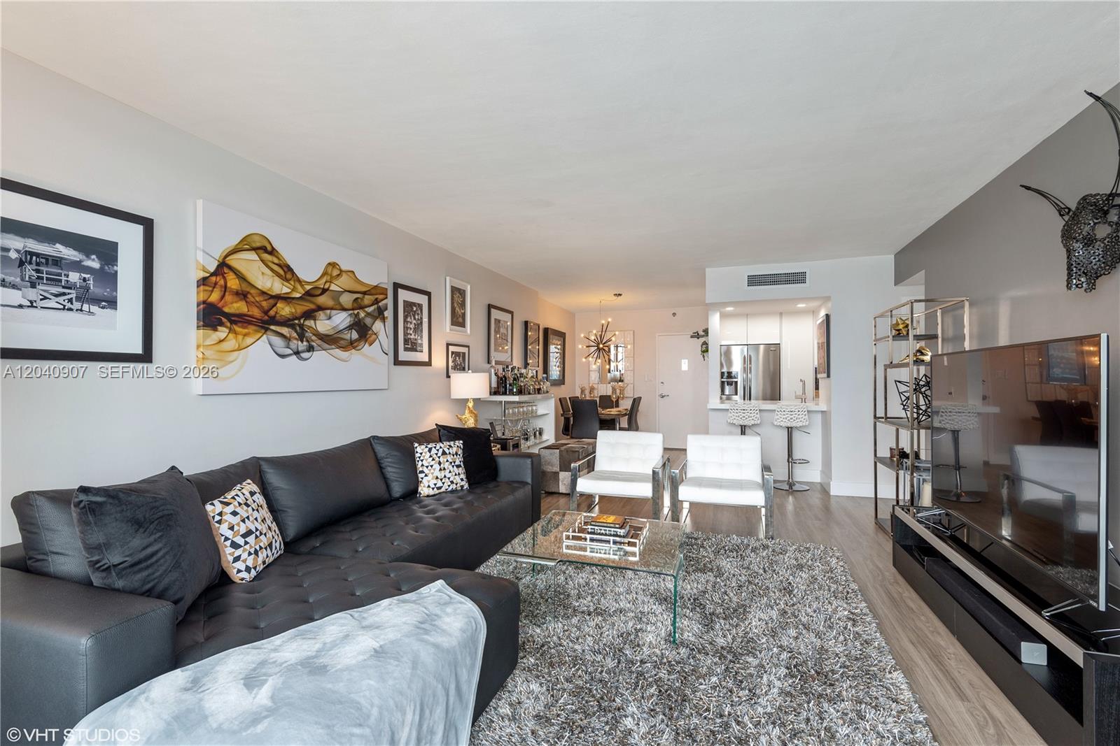 A modern living room features a black sectional sofa, white armchairs, and a glass coffee table — 1200 West Ave # 1005, Miami Beach FL 33139, MIAMI BEACH, FL