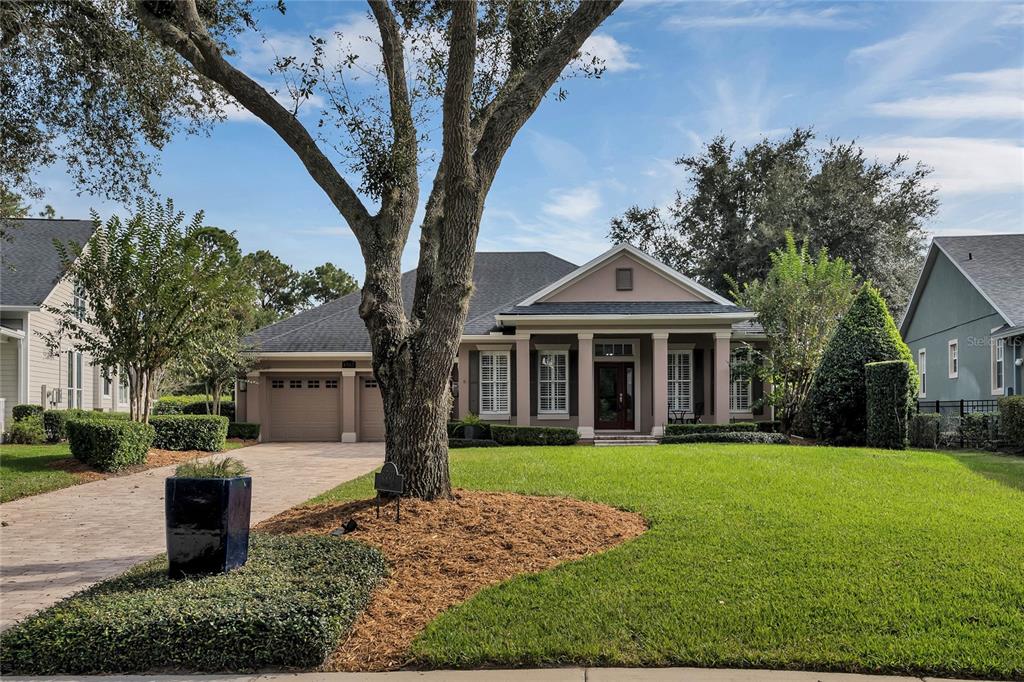 A single-story house with a tan exterior, a paved driveway, and a large front tree — 8507 BOWDEN WAY, WINDERMERE, FL