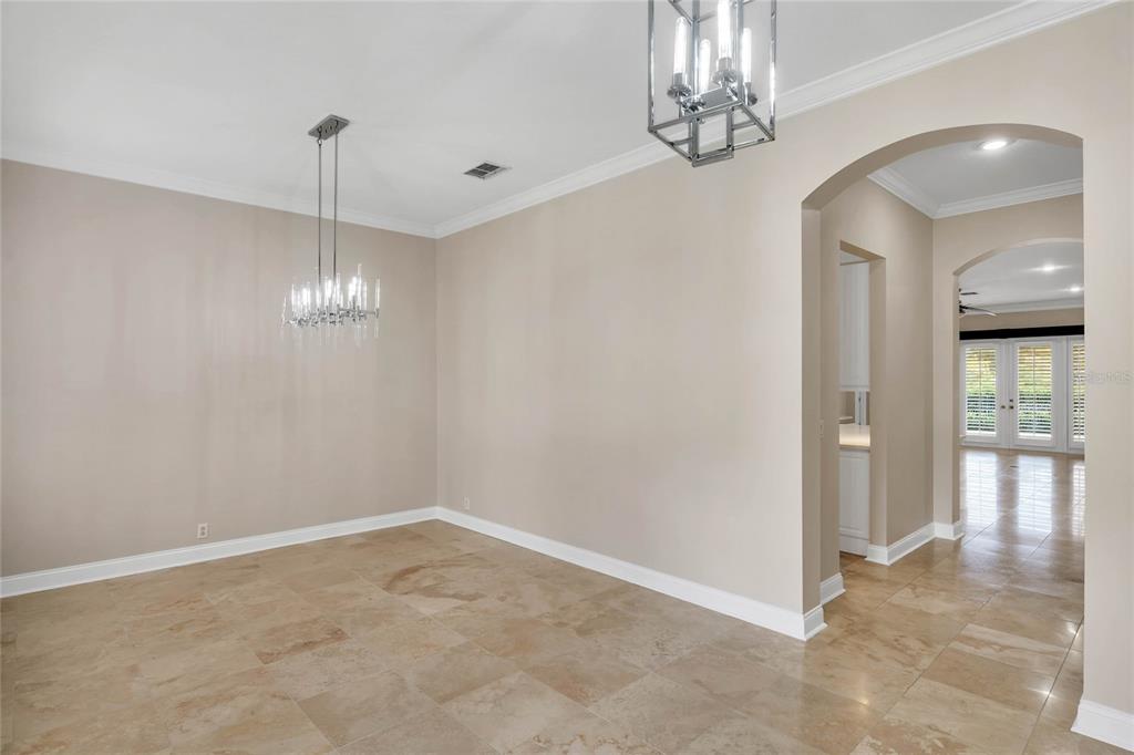 An empty dining room features beige walls, large stone floor tiles, and two modern chandeliers — 8507 BOWDEN WAY, WINDERMERE, FL