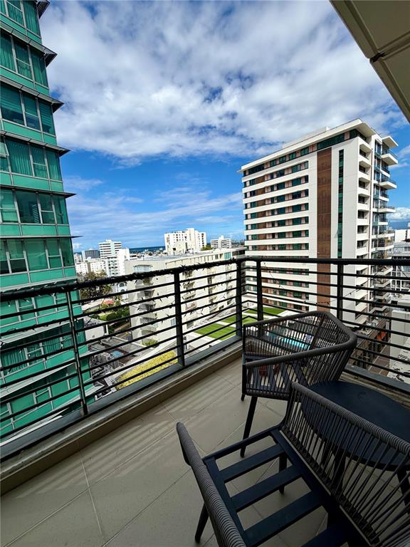 A balcony with outdoor seating overlooks a city skyline with tall apartment buildings — 1511 PONCE DE LEON AVE UNIT 7, SAN JUAN, PR