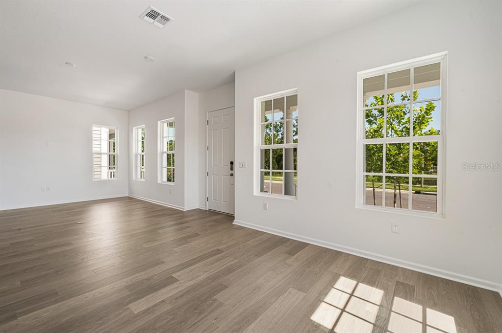 An empty room with white walls, light wood-look flooring, and several windows — 1833 HEADLAND LOOP, KISSIMMEE, FL
