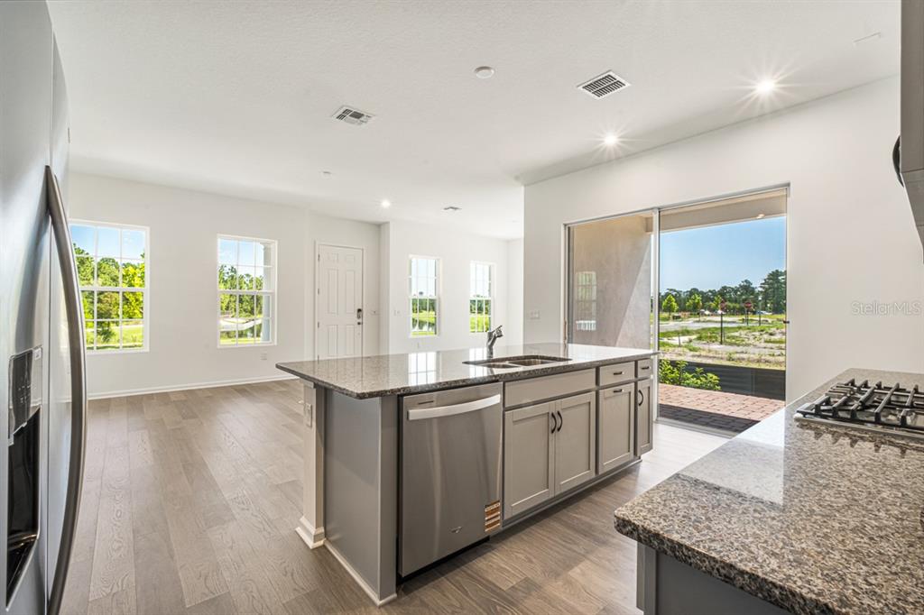 A kitchen with a granite-topped island, stainless steel appliances, and sliding glass doors to outside — 1833 HEADLAND LOOP, KISSIMMEE, FL