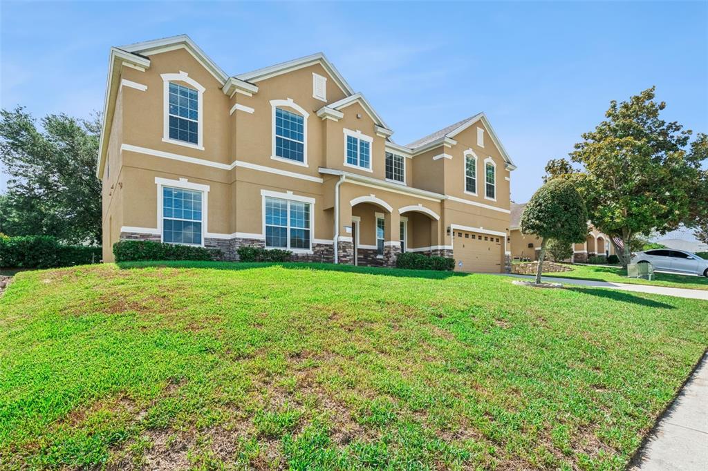A two-story house with a tan stucco exterior, stone accents, and a front-facing garage — 11121 LEMAY DRIVE, CLERMONT, FL