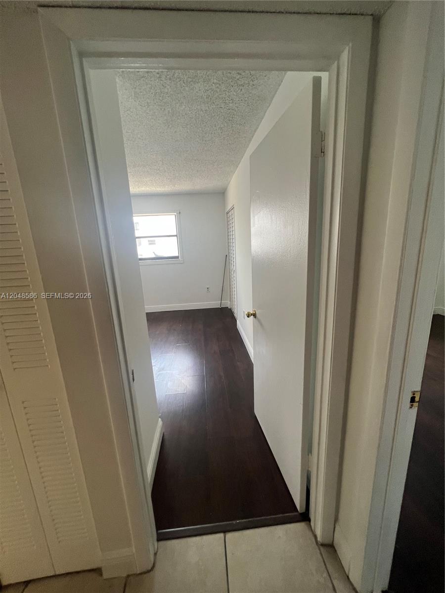 A doorway opens into a bedroom featuring dark wood flooring and a single window — 8145 NW 7th St # 405, Miami FL 33126, MIAMI, FL