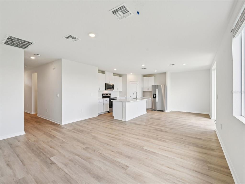 An open-concept kitchen and living area features white cabinetry, a center island, and light flooring — 11259 BELLEWOOD TERRACE, PARRISH, FL