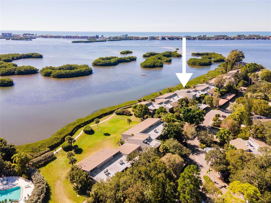 An aerial view shows a waterfront residential complex surrounded by mangroves and lush vegetation — 1520 PELICAN POINT DRIVE UNIT 155, SARASOTA, FL