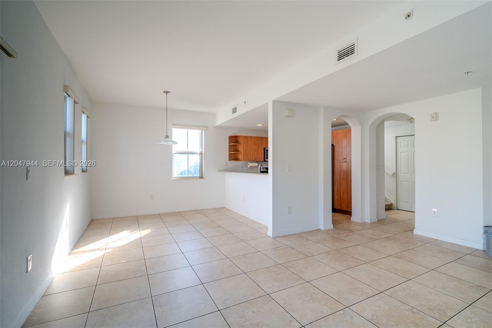 An open-concept dining area features light tile flooring, white walls, and a kitchen pass-through — 10855 NW 88th Ter # 212, Doral FL 33178, DORAL, FL