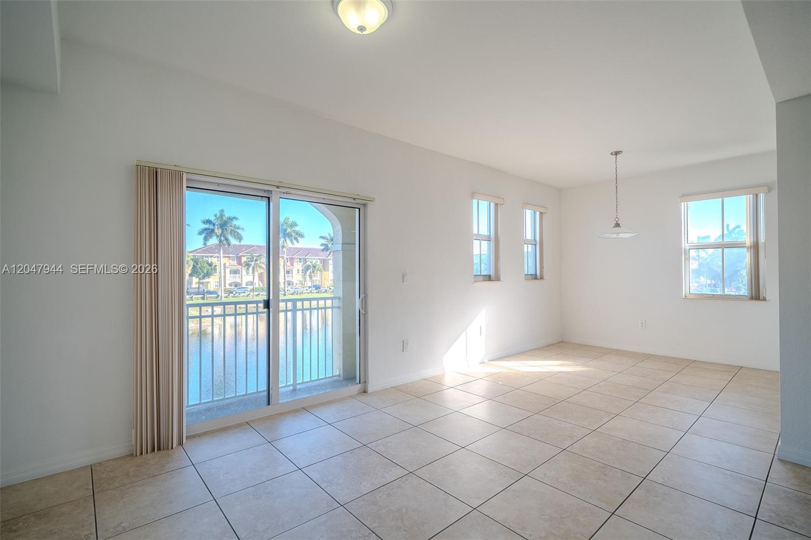 An empty room features tile flooring, a sliding glass door to a balcony, and windows — 10855 NW 88th Ter # 212, Doral FL 33178, DORAL, FL