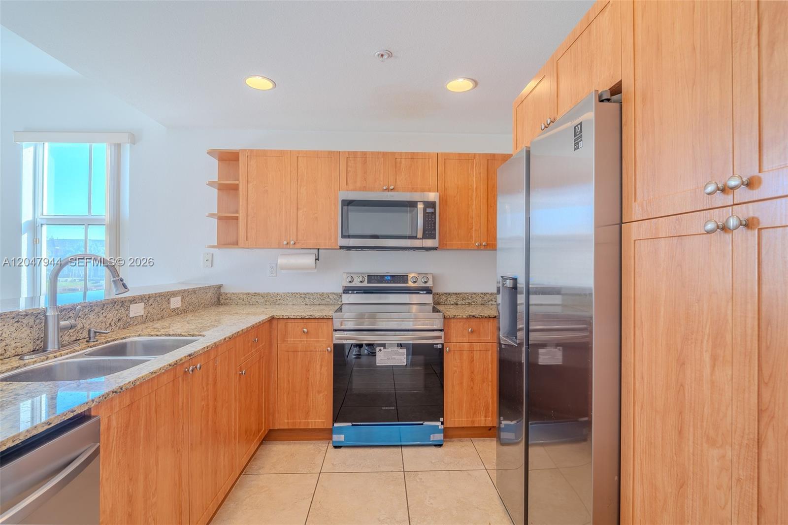 A kitchen features light wood cabinets, granite countertops, and stainless steel appliances — 10855 NW 88th Ter # 212, Doral FL 33178, DORAL, FL