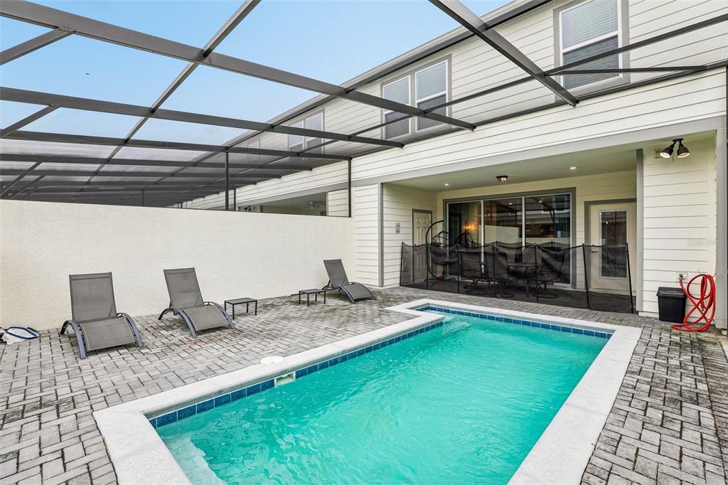 A rectangular swimming pool sits on a paved patio beneath a screened-in lanai enclosure — 4290 LANA AVENUE, DAVENPORT, FL
