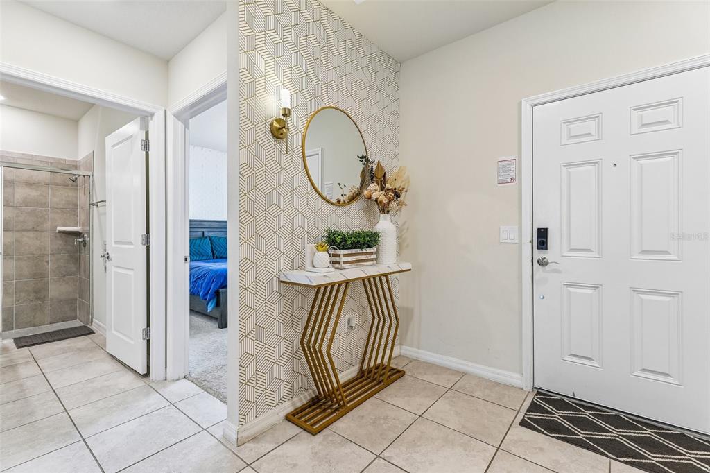 An entryway features a geometric wallpaper accent wall, a gold console table, and a mirror — 4290 LANA AVENUE, DAVENPORT, FL
