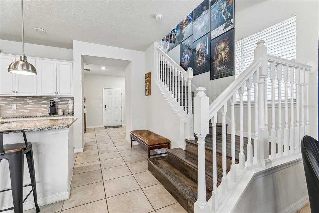 A kitchen and staircase area with tile flooring, white cabinets, and Star Wars wall art — 4290 LANA AVENUE, DAVENPORT, FL