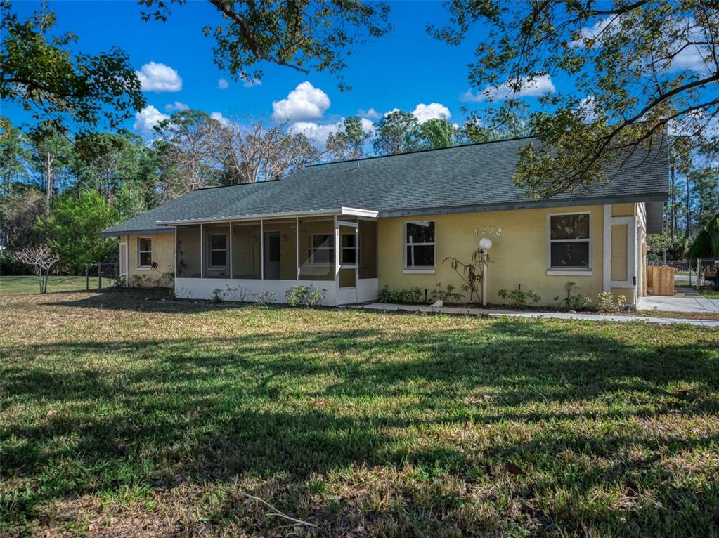 A single-story yellow house with a screened-in front porch and a dark shingled roof — 1273 WOODBURY AVENUE, SEBRING, FL