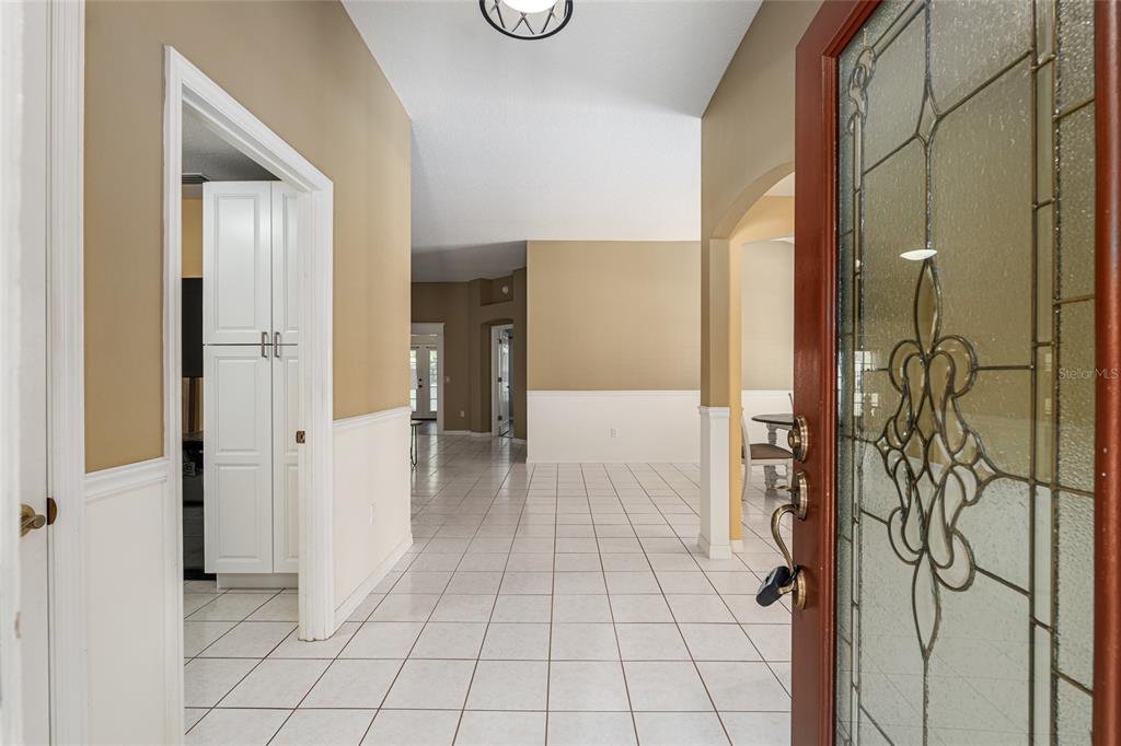 A tiled entryway leads into a home with white wainscoting and a decorative glass door — 110 CHULA VISTA AVENUE, LADY LAKE, FL