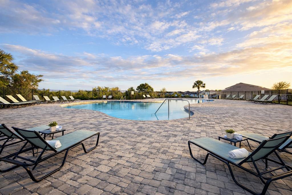 A swimming pool with lounge chairs on a paved deck under a cloudy sky — 445 MCKENNA DRIVE, WINTER HAVEN, FL